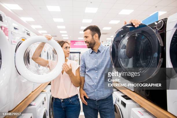 couple during house goods shopping - buying washing machine stockfoto's en -beelden