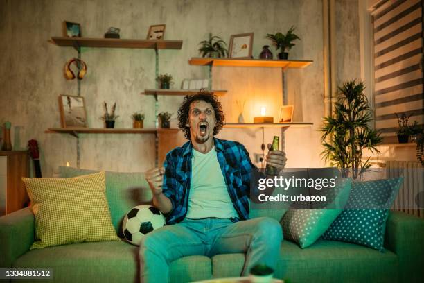 man watching soccer match on tv - man couch bildbanksfoton och bilder