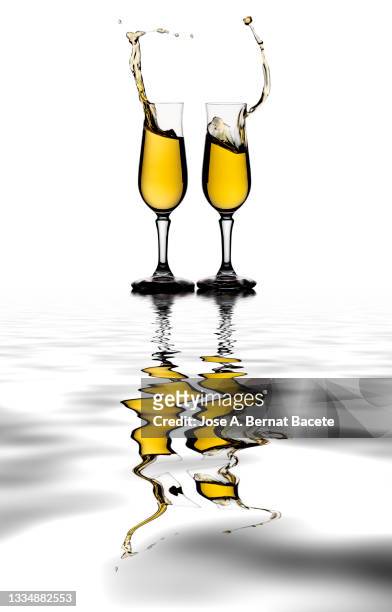 toast with two glasses of champagne on a white background, reflected on a water surface. - champagner gläser mit flasche unscharfer hintergrund stock-fotos und bilder