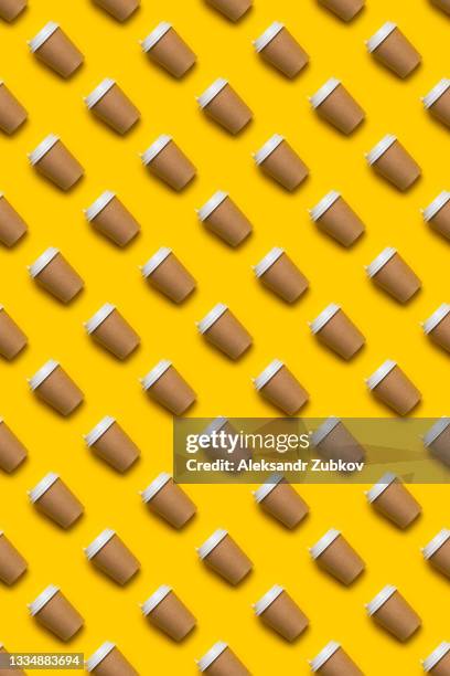 a disposable paper cup with a lid for coffee and tea on a bright pastel yellow background. coffee break. seamless background or texture, pattern and wallpaper. the concept of environmental protection. copy the space. - cafeïne stockfoto's en -beelden