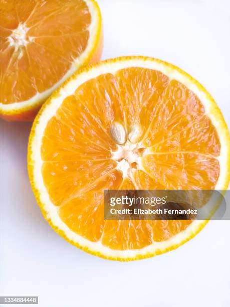 two halves of fresh orange fruit in a cut on white background. healthy and natural food concept. - cut in half ストックフォトと画像