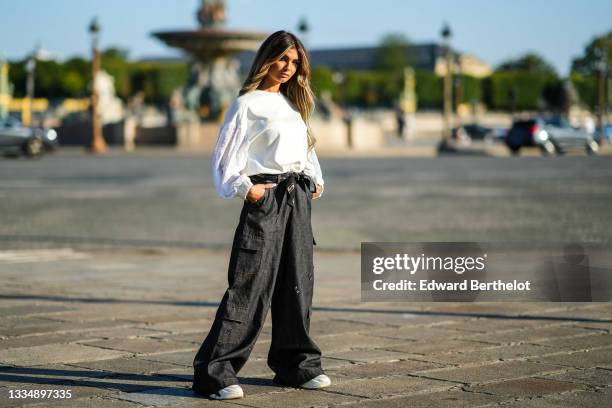 Nathanya Sonia wears a white sweater with white lace long sleeves from Alexandro Fratelli, a black scarf with brown safety pin print pattern from...
