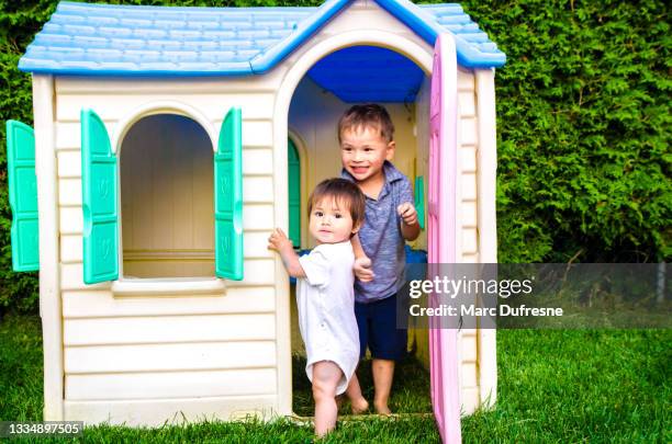 two mixed race children playing in toy house in backyard - métis stock pictures, royalty-free photos & images