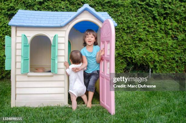 two mixed race children playing in toy house in backyard - métis stock pictures, royalty-free photos & images