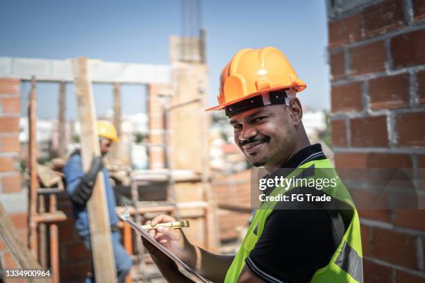 porträt eines bauarbeiters mit klemmbrett, der auf einer baustelle arbeitet - brick layer stock-fotos und bilder