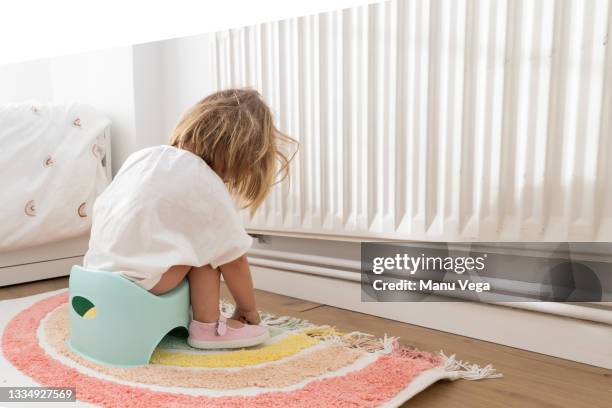 rear side view of toddler girl sitting on a potty - child urinating stockfoto's en -beelden