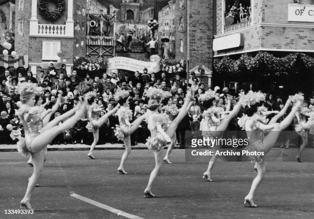 High-kicking young ladies during the Macy's Day Parade at Thanksgiving in New York City, 26th November 1961. A number of tableaux behind commemorate...