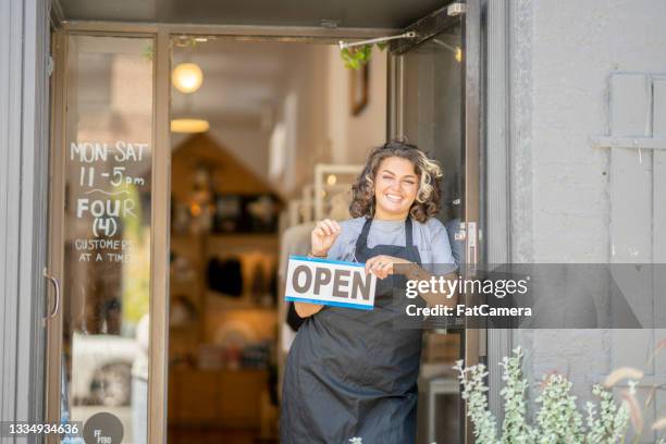 young female small business owner reopening her store after lockdown - store opening covid stock pictures, royalty-free photos & images