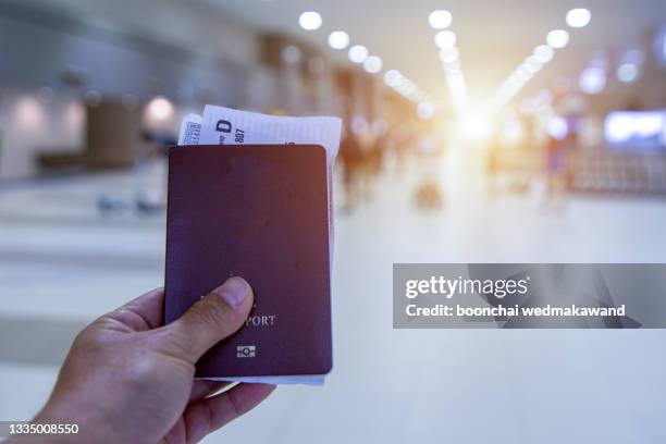 closeup of man hand holding passports and boarding pass at airport. - パスポート ストックフォトと画像