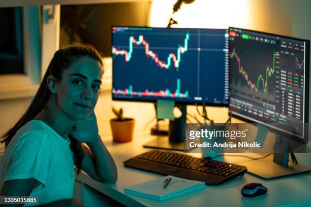 portrait of a smiling young female trader working at home late night - stock trader stock pictures, royalty-free photos & images