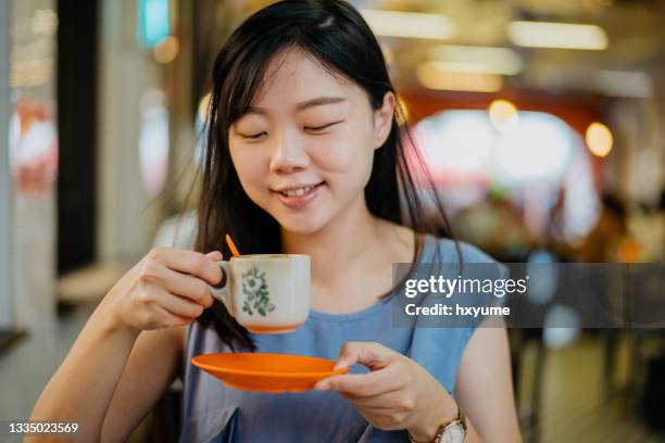 young woman drinking malaysian style traditional coffee - singaporean culture stock pictures, royalty-free photos & images