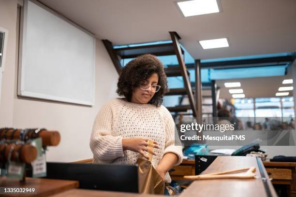 saleswoman placing merchandise in the shopping bag - plus size fashion stock pictures, royalty-free photos & images