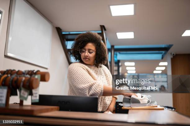 saleswoman putting shoes in shopping bag - shoe shop assistant stock pictures, royalty-free photos & images