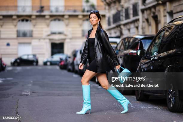 Ketevan Giorgadze @katie.one wears black oversized sunglasses from Prada, large silver chain and rhinestones pendant earrings, a black V-neck little...