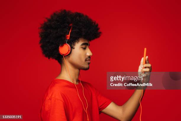 african american man with african hairstyle  standing over isolated red background - red headphones stock pictures, royalty-free photos & images