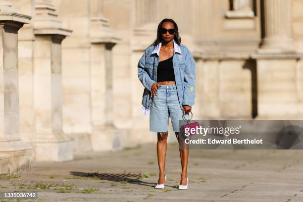 Emilie Joseph @in_fashionwetrust wears black oversized sunglasses, a pale blue and white striped long shirt, a blue faded denim oversized jacket with...