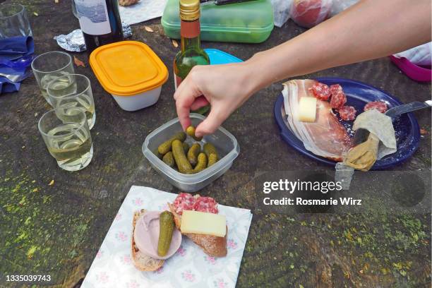 picnic display seen from above, hand choosing pickled gherkin - sliced pickles stockfoto's en -beelden