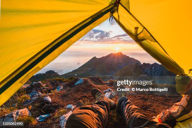 personal perspective of person relaxing in a tent looking at sunset on mountain top, senja, norway - shoes top view stockfoto's en -beelden