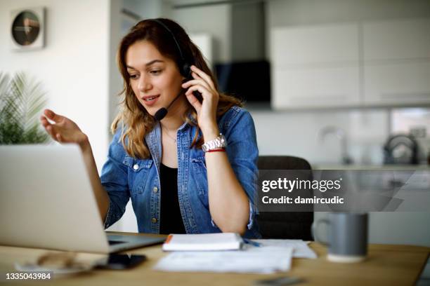 junge frau mit headset und laptop im homeoffice - freisprechanlage stock-fotos und bilder