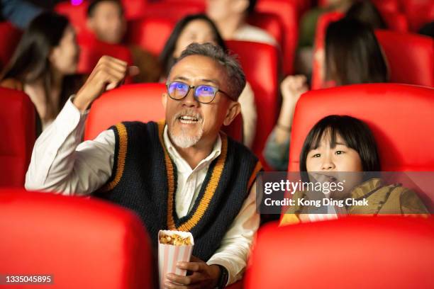 asian chinese grandfather and granddaughter together with group of audience watching movie in cinema enjoying the show excitement - asian cinema stock pictures, royalty-free photos & images