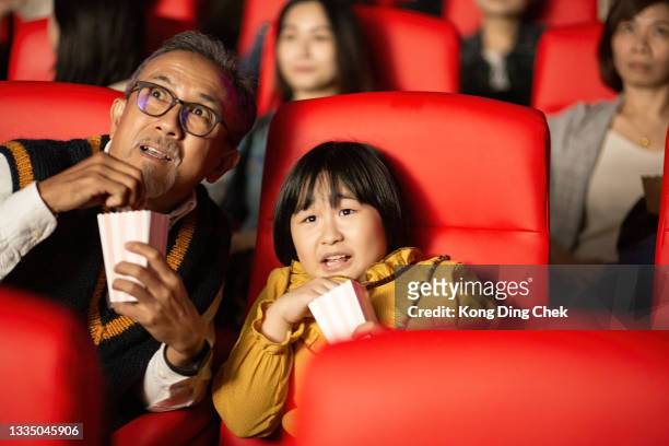 asian chinese grandfather and granddaughter together with group of audience watching movie in cinema enjoying the show excitement - asian cinema bildbanksfoton och bilder