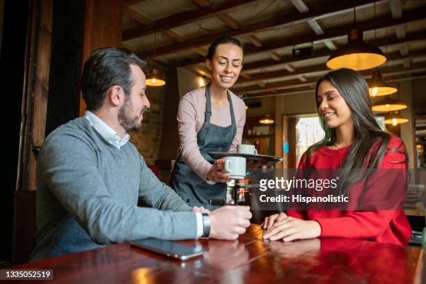 cameriera che serve caffè a un paio di clienti in un bar - man eating at diner counter foto e immagini stock