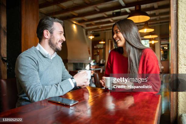 happy couple drinking a cup of coffee at a cafe - coffee shop couple stock pictures, royalty-free photos & images