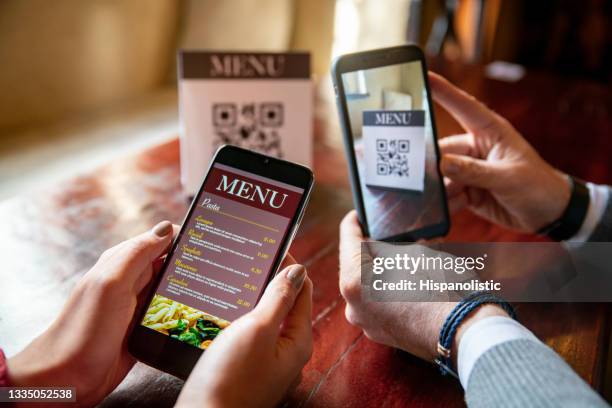 couple at a restaurant scanning the menu with qr codes using their cell phones - bar code imagens e fotografias de stock