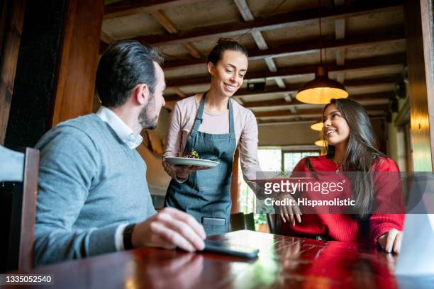 cameriera che serve cibo ai clienti in un ristorante - man eating at diner counter foto e immagini stock