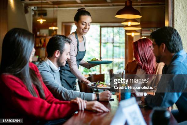 cameriera che serve cibo a un gruppo di clienti in un ristorante - man eating at diner counter foto e immagini stock