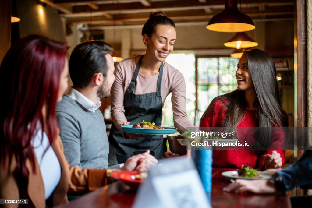 Kellnerin, die einer Gruppe von Kunden in einem Restaurant Essen serviert