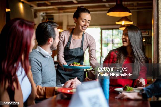 camarera que sirve comida a un grupo de clientes en un restaurante - eating food happy fotografías e imágenes de stock