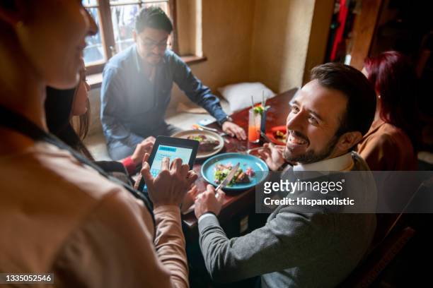 uomo felice che mangia con gli amici in un ristorante e ordina alla cameriera - man eating at diner counter foto e immagini stock