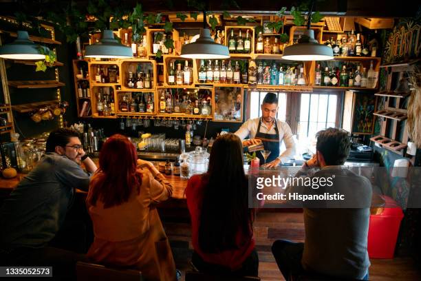barkeeper an der bar, der cocktails für menschen zubereitet - horizontal bars stock-fotos und bilder