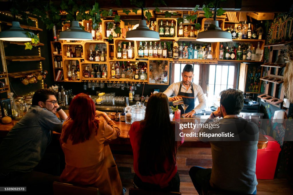Bartender at the bar making cocktails for people