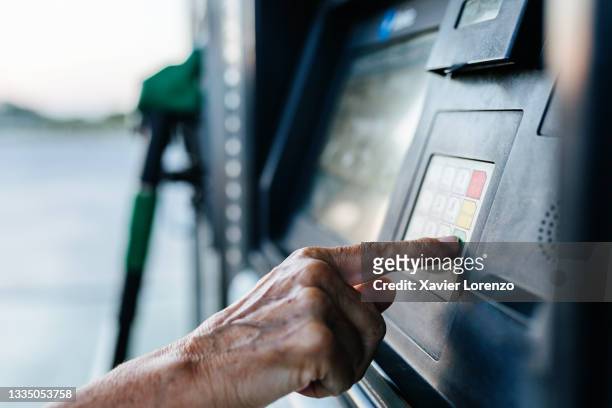 senior woman paying for the fuel with a credit card at the gas sta - social & economic life stock pictures, royalty-free photos & images