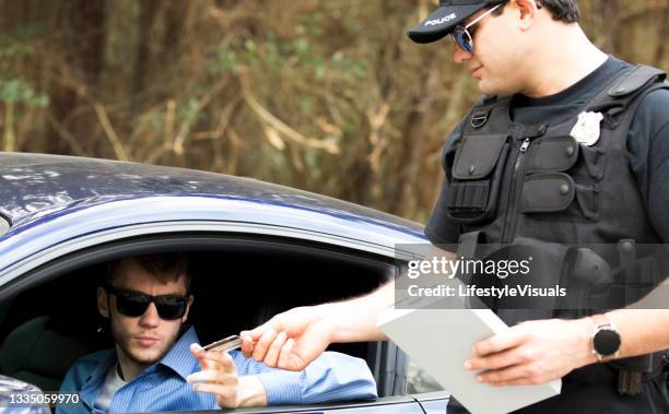 friendly police officer stops a young man on a rural road. - pulled over by police stock pictures, royalty-free photos & images