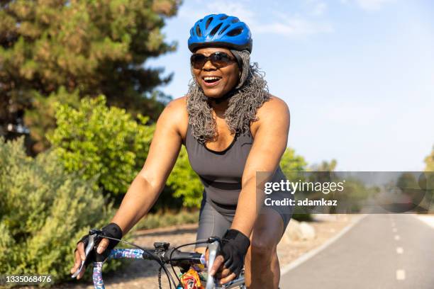 senior black woman riding bicycle - black woman riding bike imagens e fotografias de stock