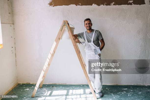 portrait of a smiling young man plastering wall in his workshop - decorating stock pictures, royalty-free photos & images