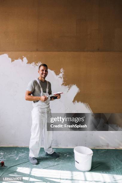 portrait of a happy young man plastering wall in his workshop - plasterer stock pictures, royalty-free photos & images