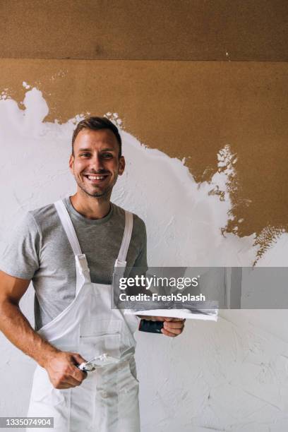 portrait of a happy young man plastering wall in his workshop - spatula stock pictures, royalty-free photos & images