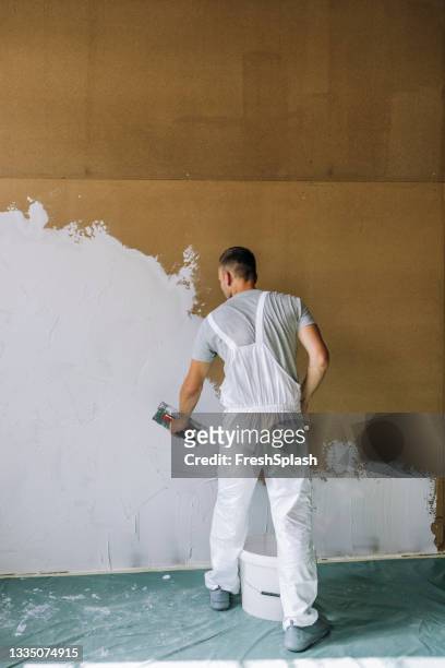 back view of an anonymous man plastering wall with spatula - plasterer stock pictures, royalty-free photos & images