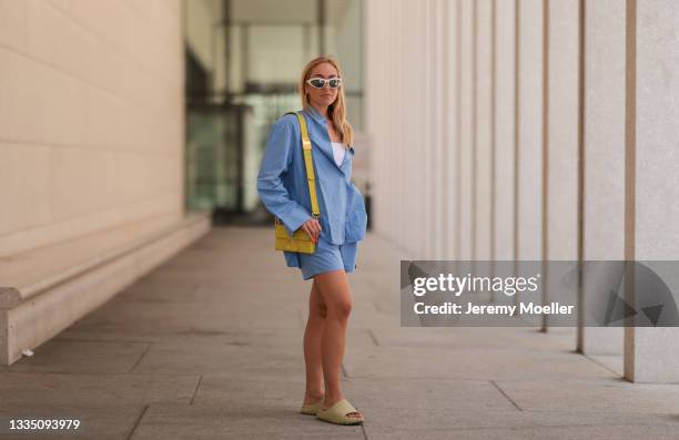 Sonia Lyson wears Yeezy beige slides, The Frankie Shop blue two piece, Bottega Veneta white shades and Dior bag on August 16, 2021 in Berlin, Germany.