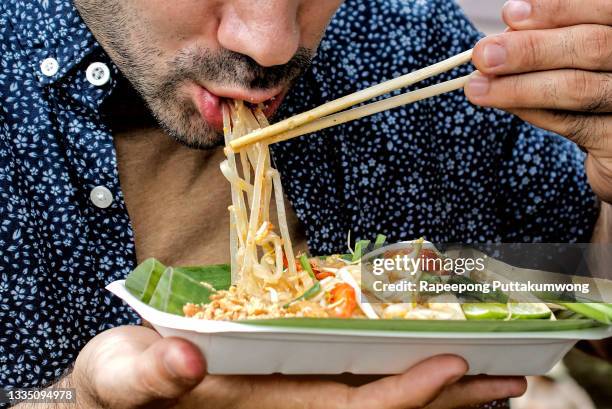 tourists eating pad thai. traditional street food in thailand - thai food fotografías e imágenes de stock