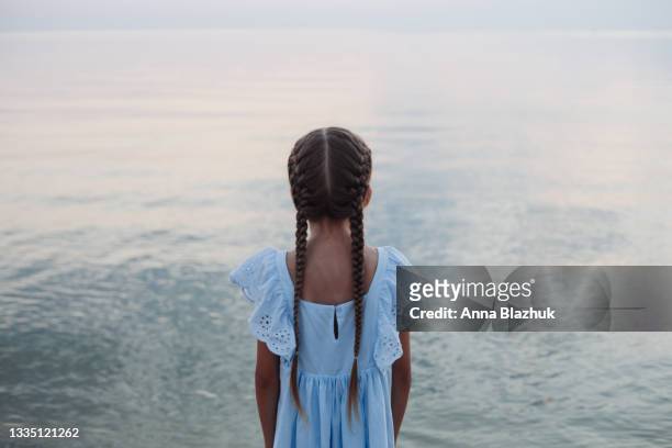 summer portrait of little girl of 9 years old with long braided hair in blue dress by the sea. child's picture. - 8 9 years stock-fotos und bilder
