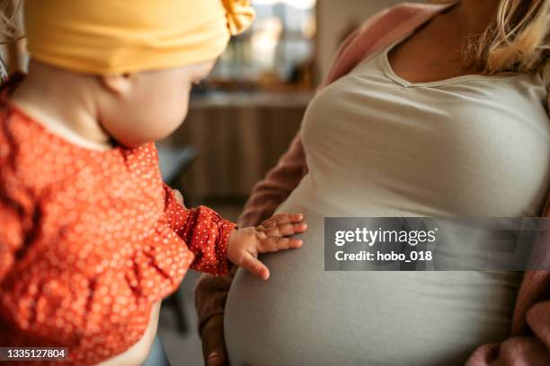 cute baby girl touching pregnant belly of her mother. - maternity wear stock pictures, royalty-free photos & images