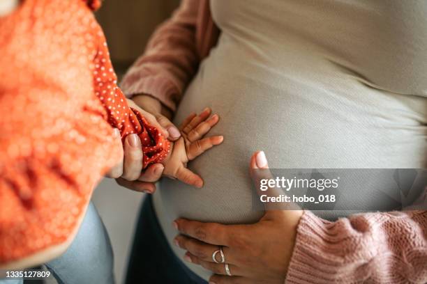 süßes baby mädchen berührt schwangeren bauch ihrer mutter. - sibling stock-fotos und bilder