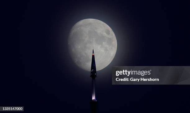 Percent waxing gibbous moon rises behind the antenna on top of One World Trade Center ahead of this weekend's full sturgeon and blue moon in New York...