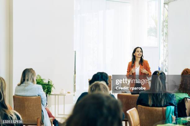 chica con ropa naranja habla a su público - announcement fotografías e imágenes de stock