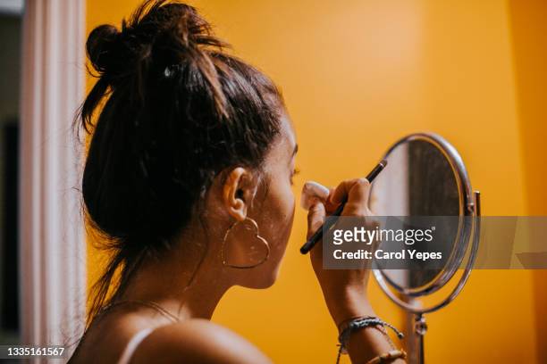 a young woman applies powder foundation in the bathroom in front of the mirror - make up bag stock pictures, royalty-free photos & images
